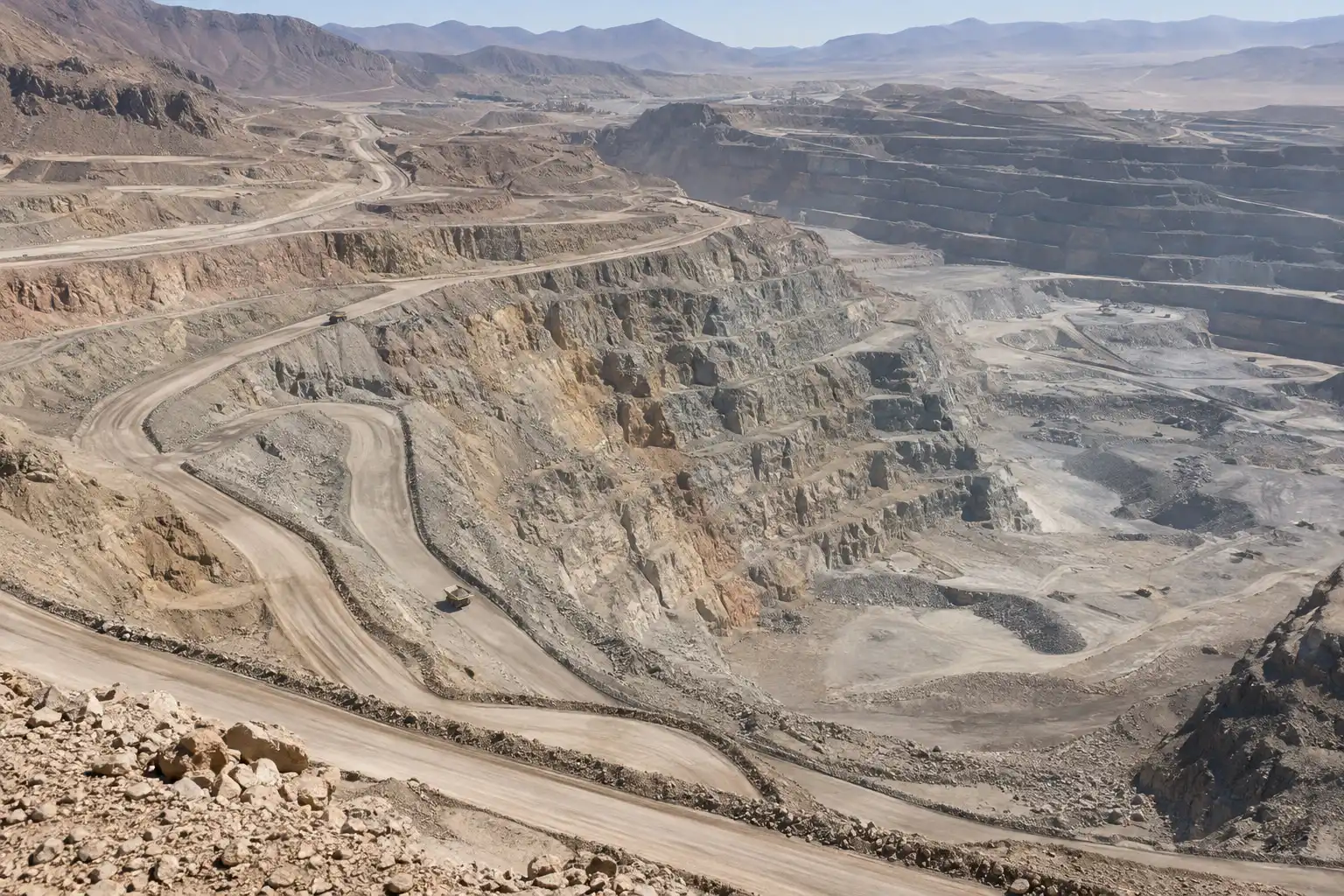 Vista aérea de un rajo minero con bancos, rampas y caminos de acarreo